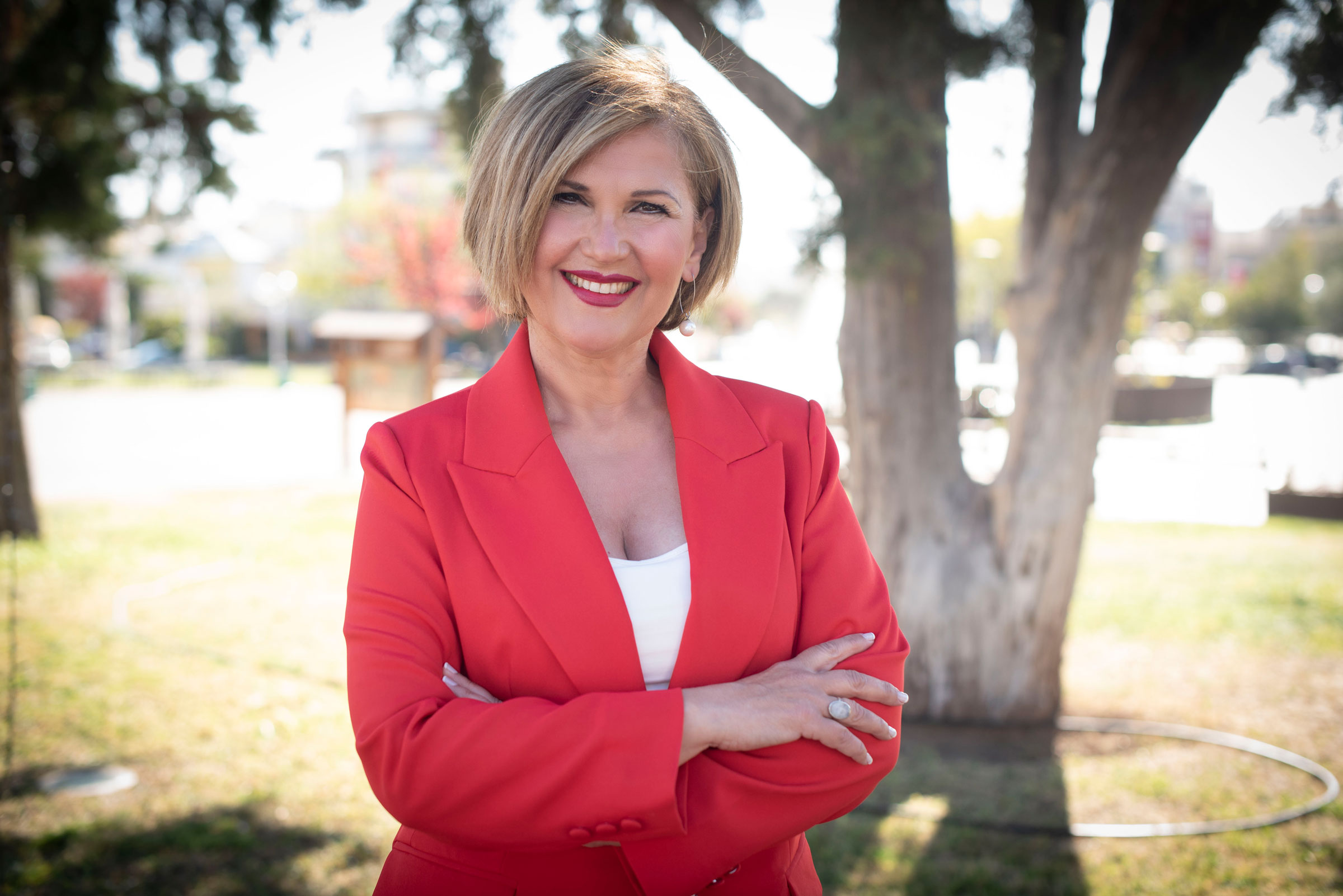 Portrait of Sofia Vasilara smiling outdoors, wearing a red blazer, conveying confidence and approachability for her personal brand